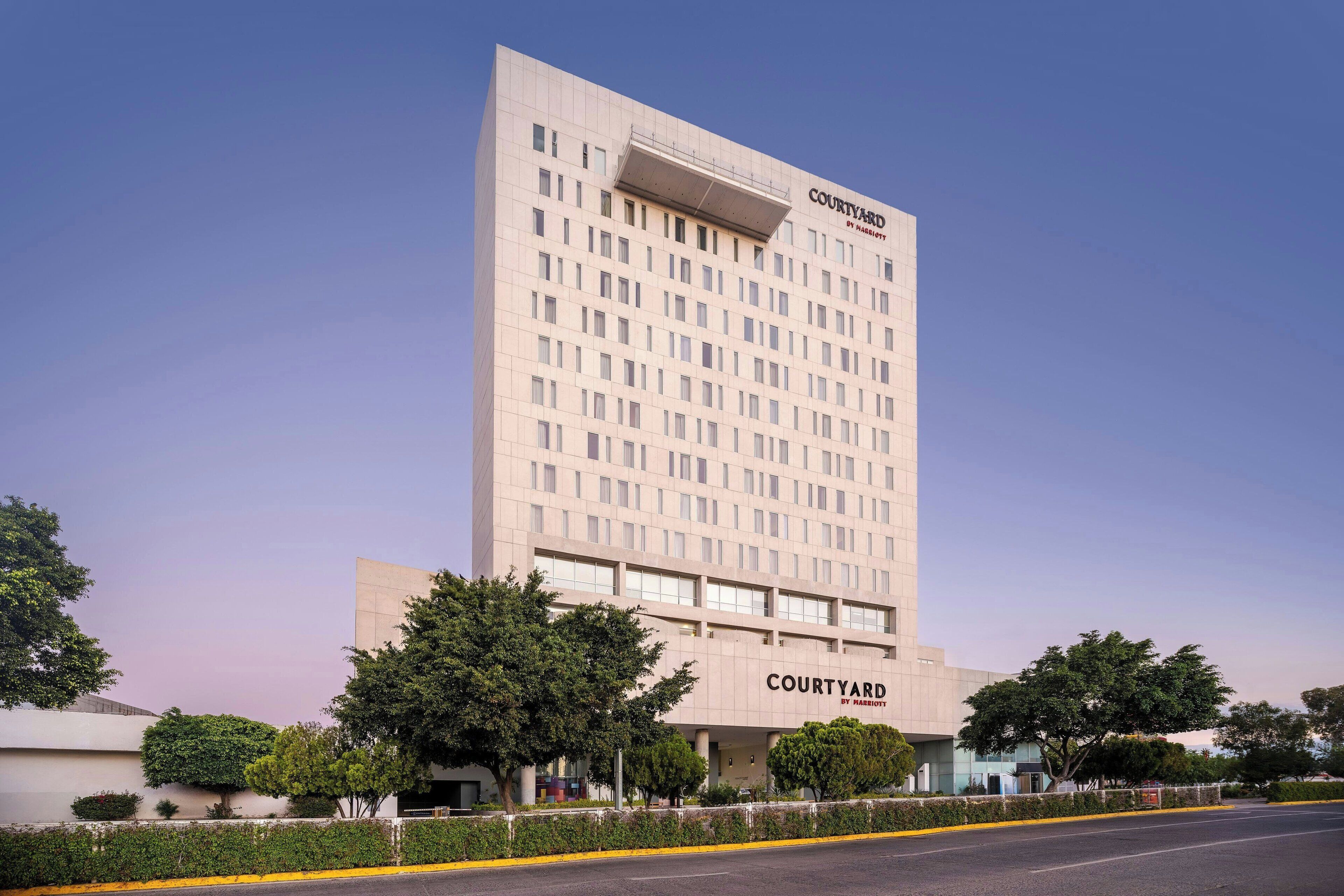 A Courtyard by Marriott hotel with a modern design, featuring a prominent entrance and a large parking area.