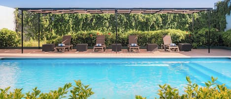 A poolside area with lounge chairs and a pergola.