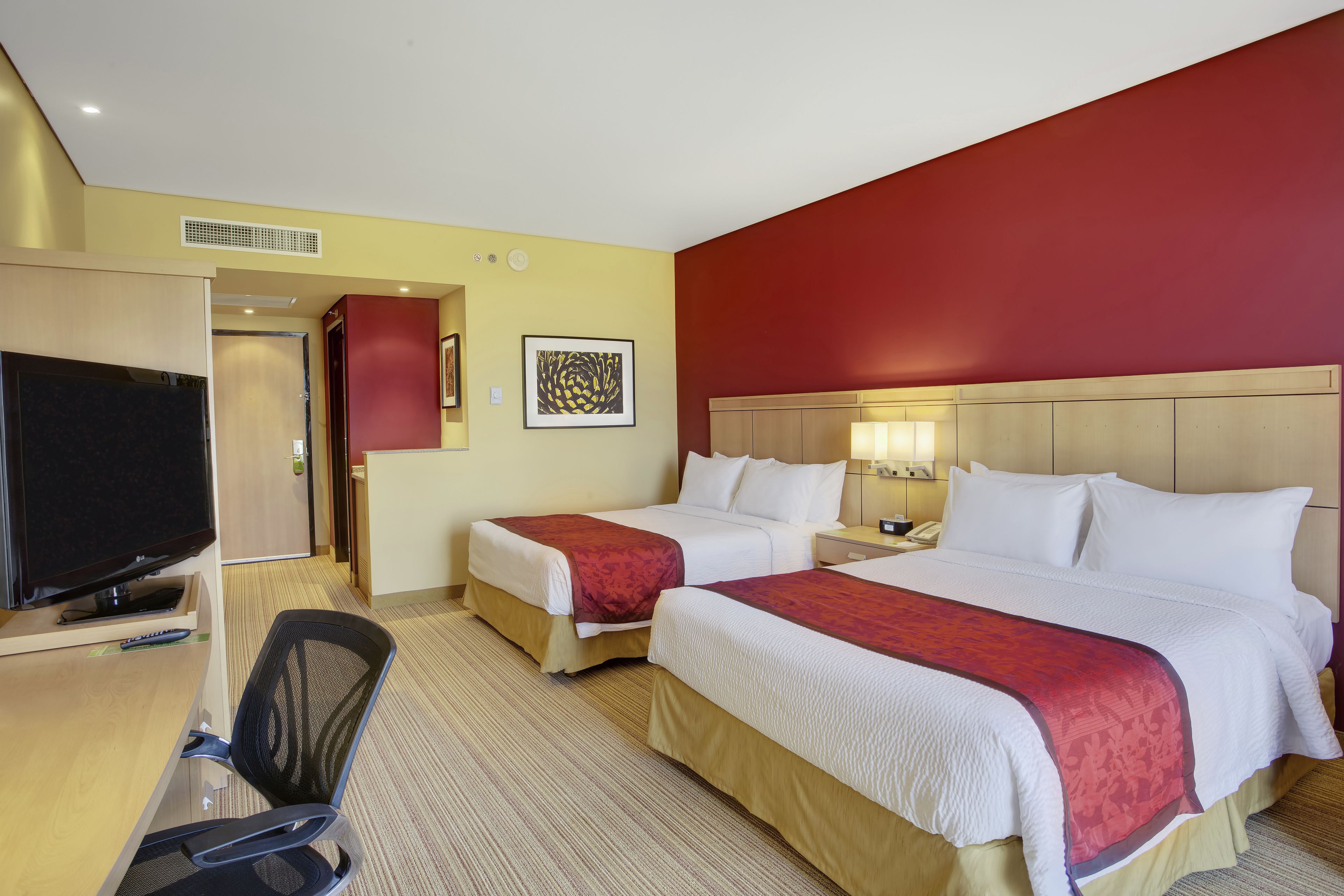 A hotel room with two beds, a desk with a computer, and a TV.