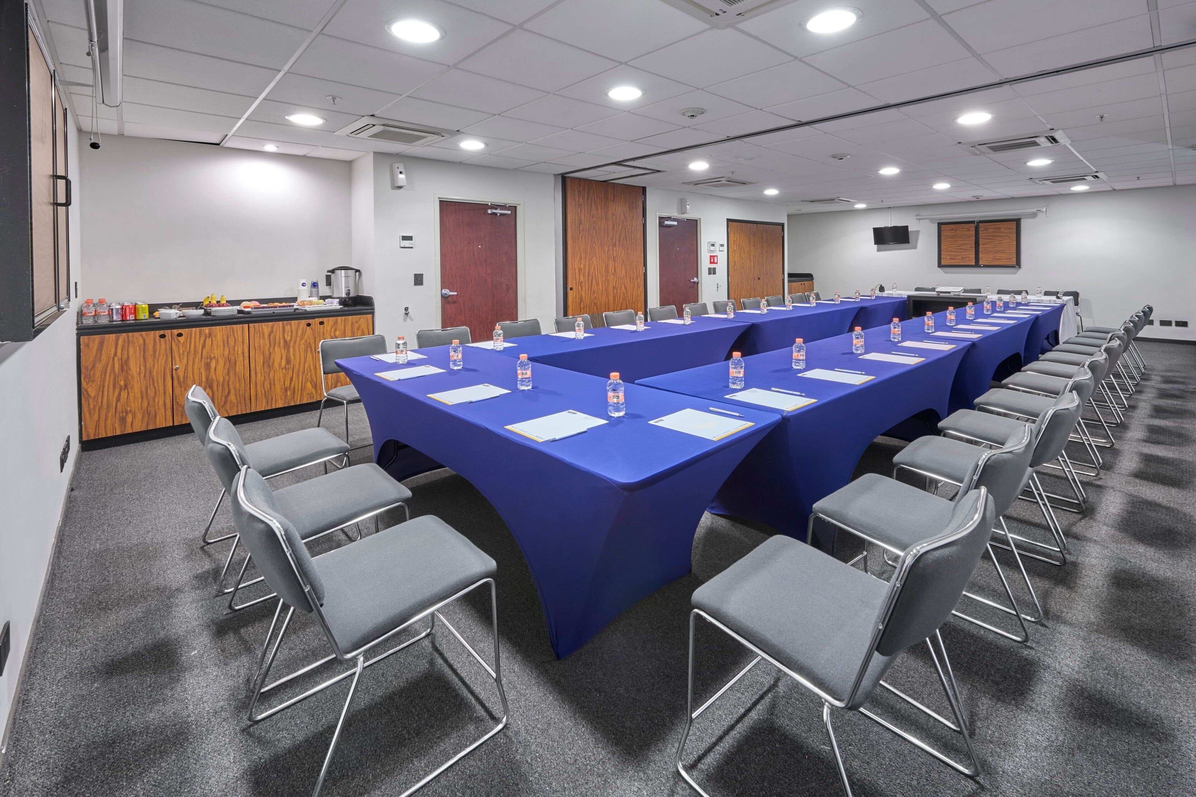 Un salón de conferencias con una larga mesa, sillas y una zona de bufé.