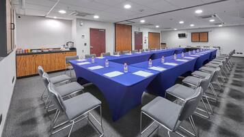 Un salón de conferencias con una larga mesa, sillas y una zona de bufé.