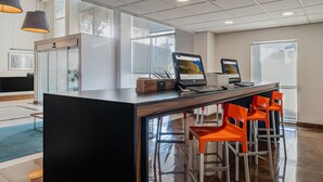 A modern reception area with a wooden reception desk, two laptops, and orange bar stools. - City Express by Marriott Querétaro Juríca (Querétaro)