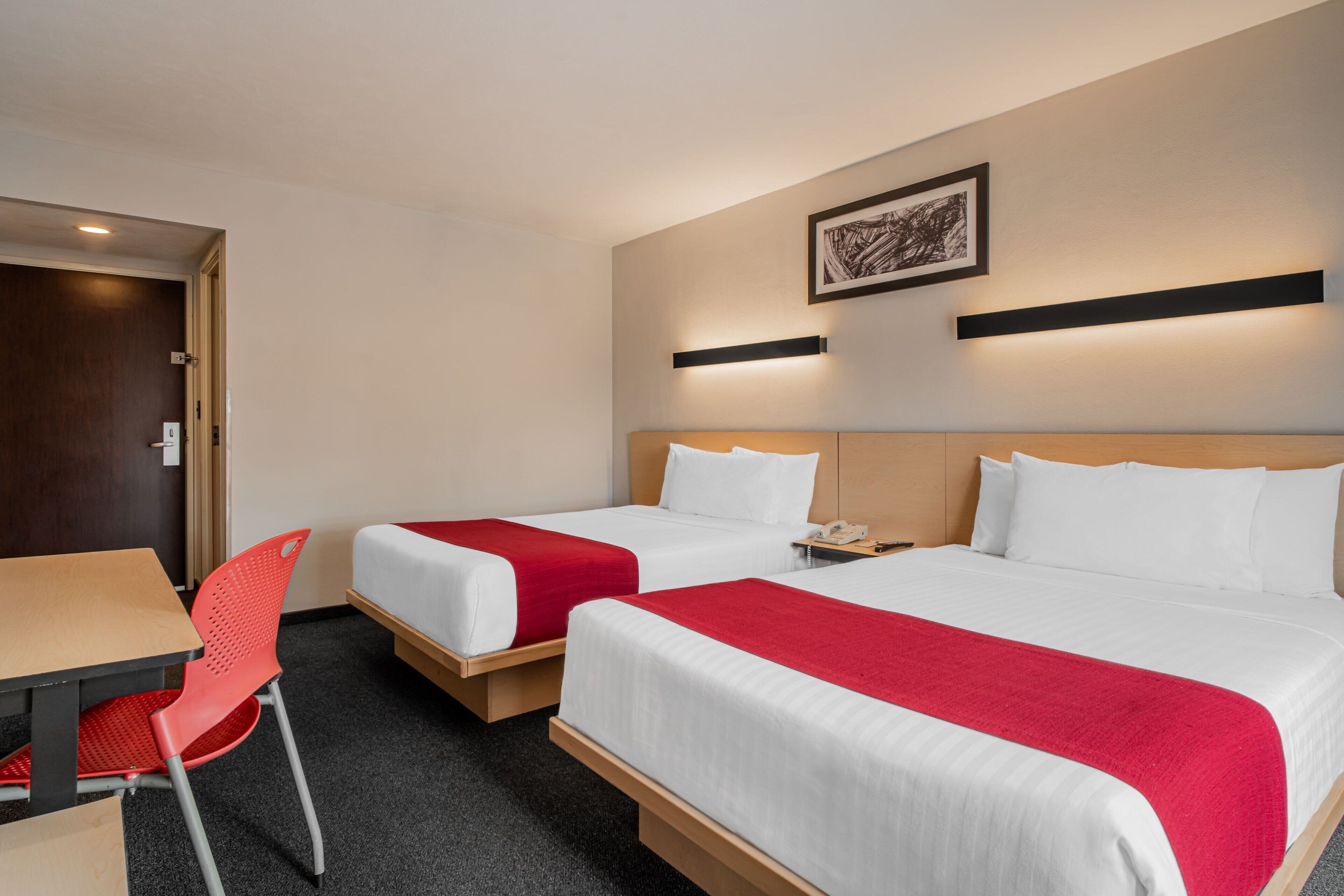 A hotel room with two beds, a desk, a chair, and a nightstand.