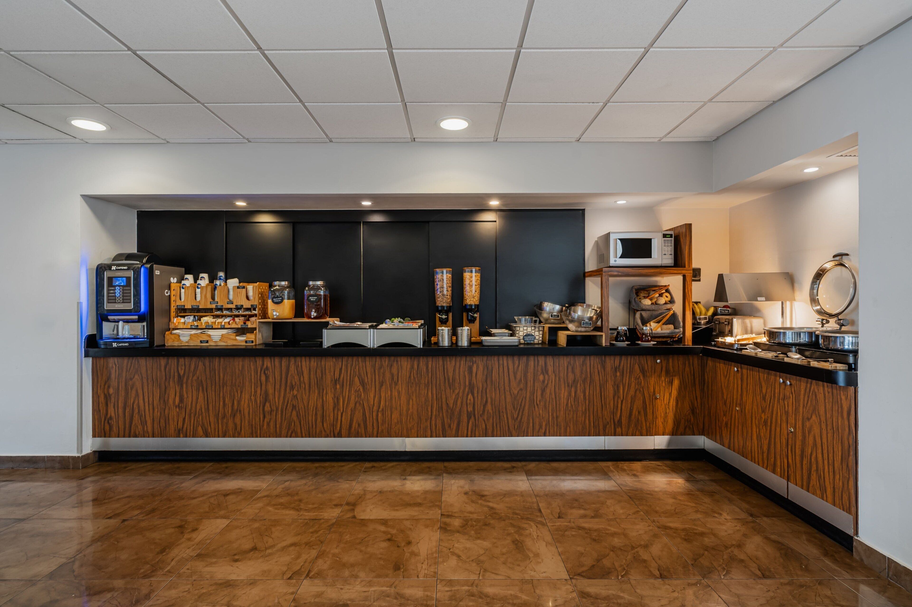 A modern kitchen with a wooden counter, coffee machines, and a microwave.