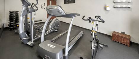Un gimnasio con cintas de correr, elípticas y una bicicleta estática.