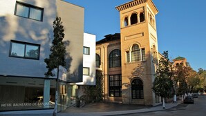 Een hotel met een moderne gevel en een historische toren.