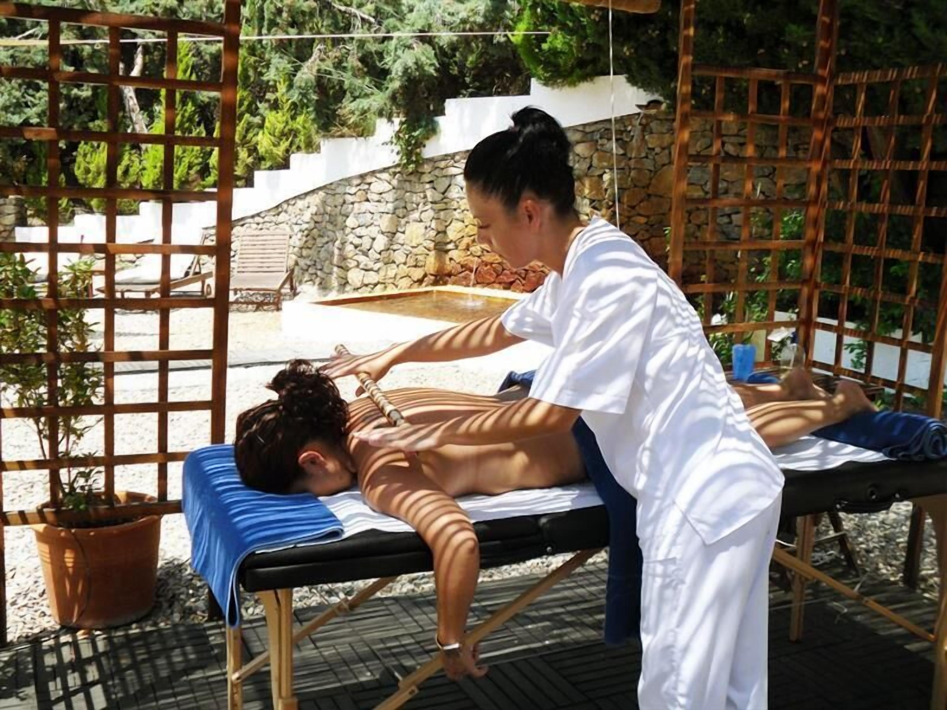 Une séance de massage en plein air, avec un mur de pierres et de la verdure en arrière-plan.