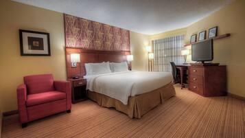 A hotel room with a bed, a desk, a chair, and a TV.