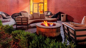 An outdoor patio with a fire pit, seating area, and brick walls. - Courtyard Killeen Marriott (Killeen)