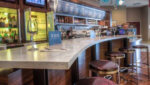 A bar area with a marble countertop, stools, and a menu board. - Courtyard Killeen Marriott (Killeen)
