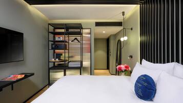 A modern hotel room with a bed, a desk, and a TV.