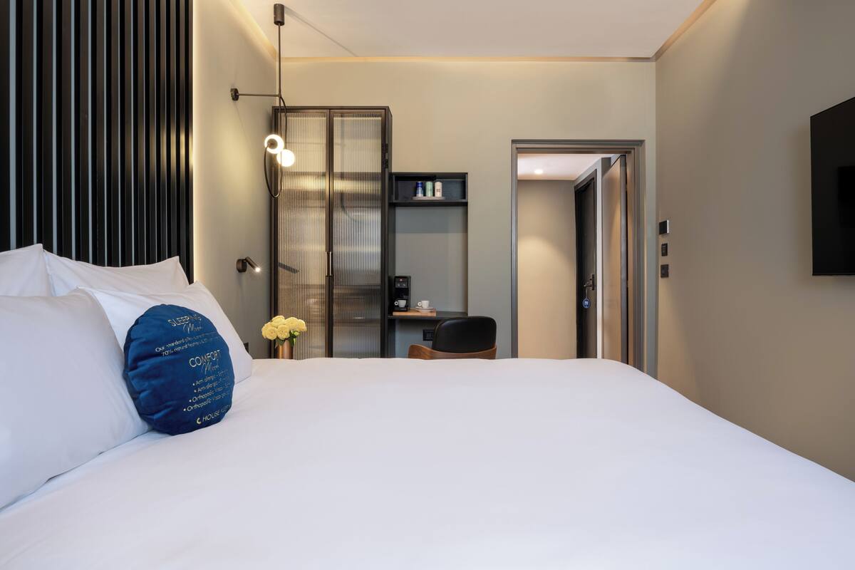 Une chambre d’hôtel équipée d’un lit, d’un bureau, d’une chaise, d’une armoire et d’un téléviseur fixé au mur.