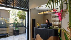 Balcão de recepção com computador, vitrine de vidro com objetos e planta em vaso.