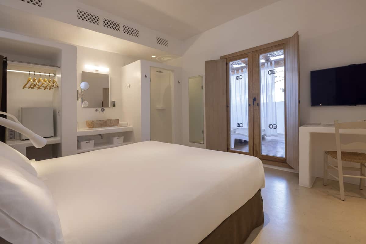 Une chambre d’hôtel équipée d’un lit, d’un bureau, d’une télévision, d’un miroir et d’une salle de bain avec douche et toilettes.