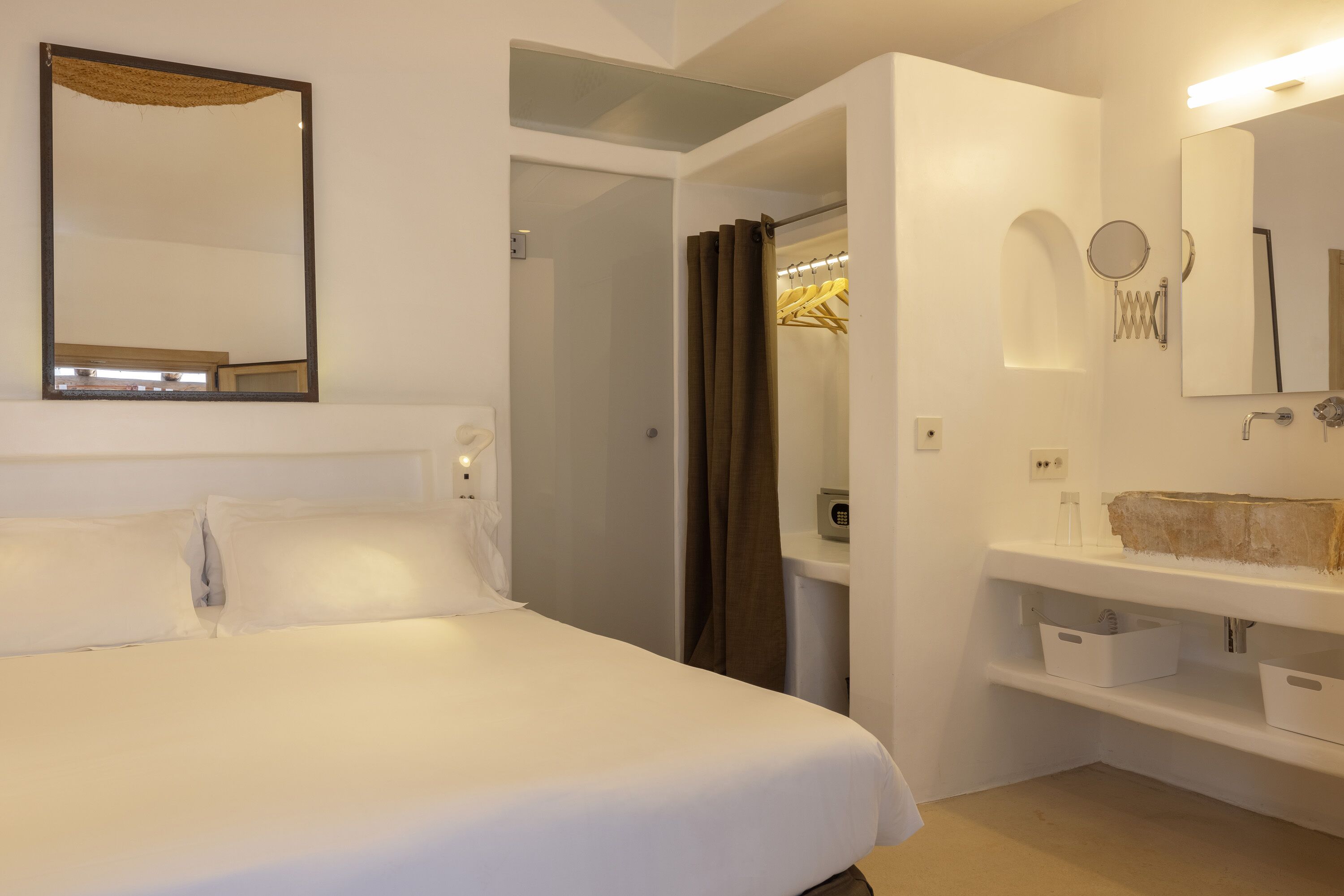 Una habitación de hotel con cama, baño con espejo y zona de ducha.