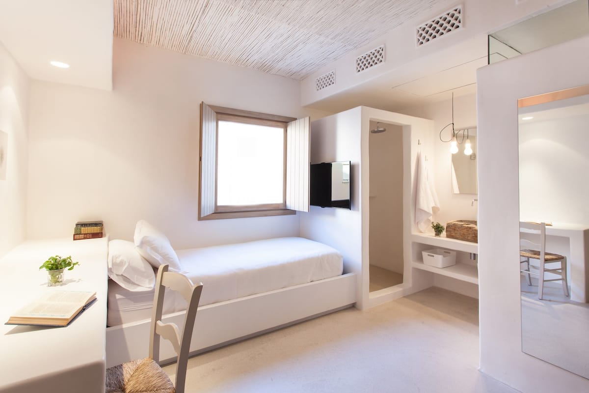 Une chambre à coucher moderne avec un lit, une table de chevet et un petit espace bureau.