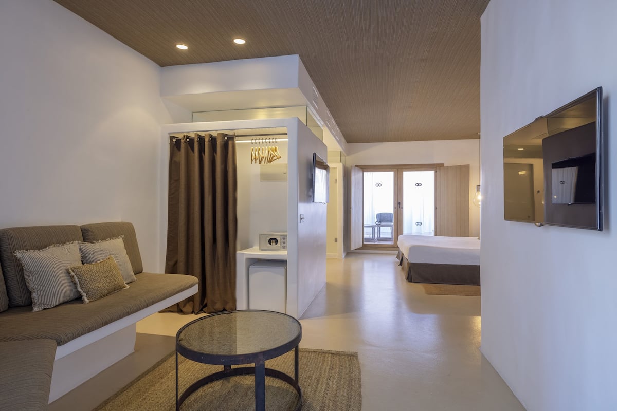 Une chambre d’hôtel moderne équipée d’un canapé, d’une petite table, d’un bureau et d’un lit.