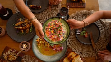 Una mesa de comedor con varios platos de comida, una vela y una copa de vino.