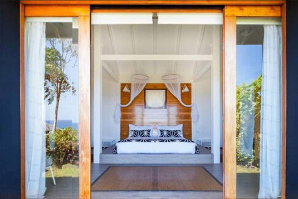 Quarto com cama, dossel e vista para o exterior.