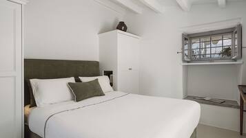 A bedroom with a bed, a nightstand, a window with a view, and a door.