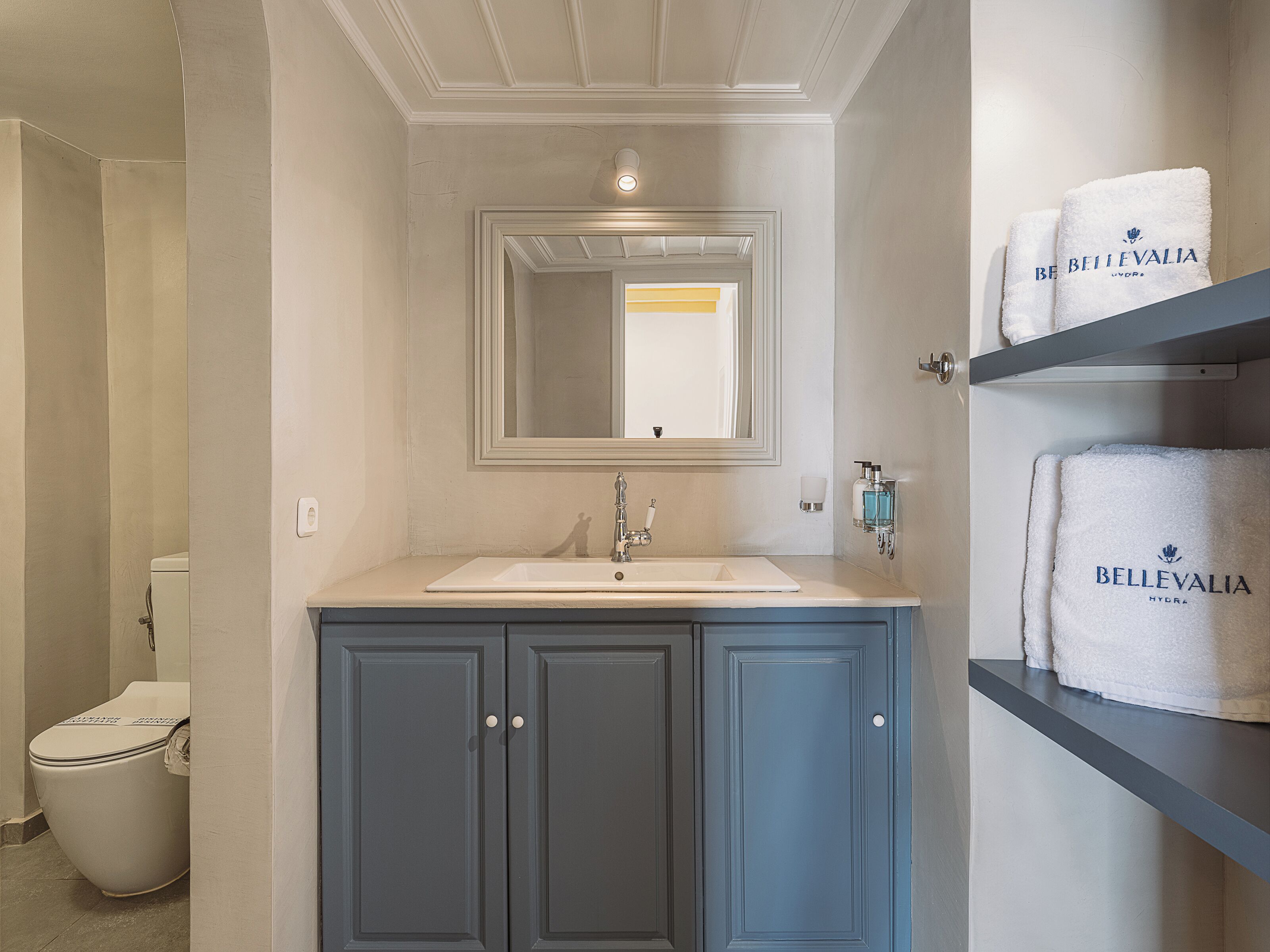 A bathroom with a white sink, a mirror above it, and a towel rack with towels.