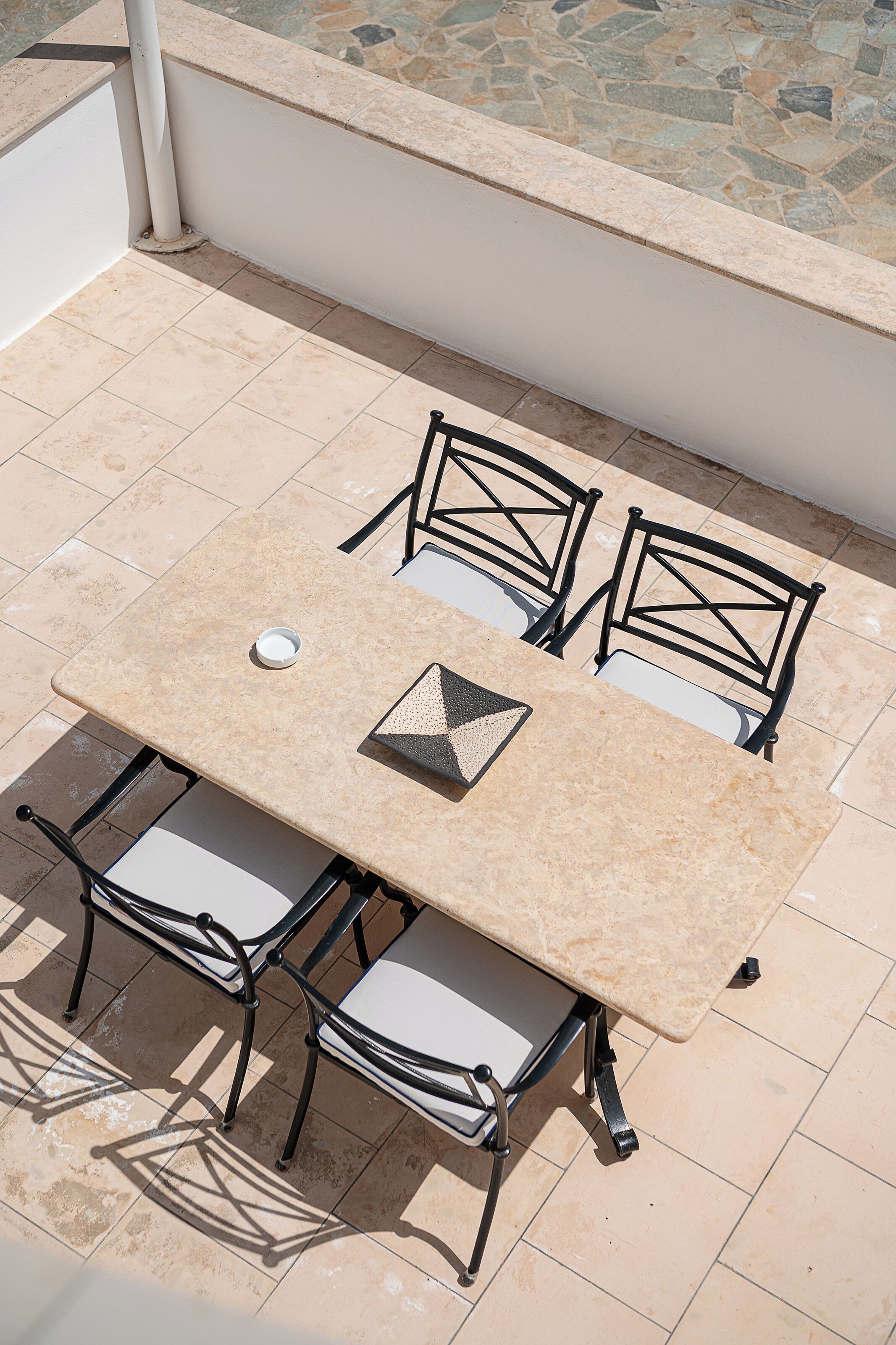Une table avec quatre chaises, une nappe blanche et un petit objet blanc posé sur la table.
