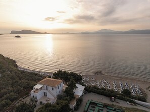Una propiedad costera con una casa, mobiliario exterior y vista al mar.