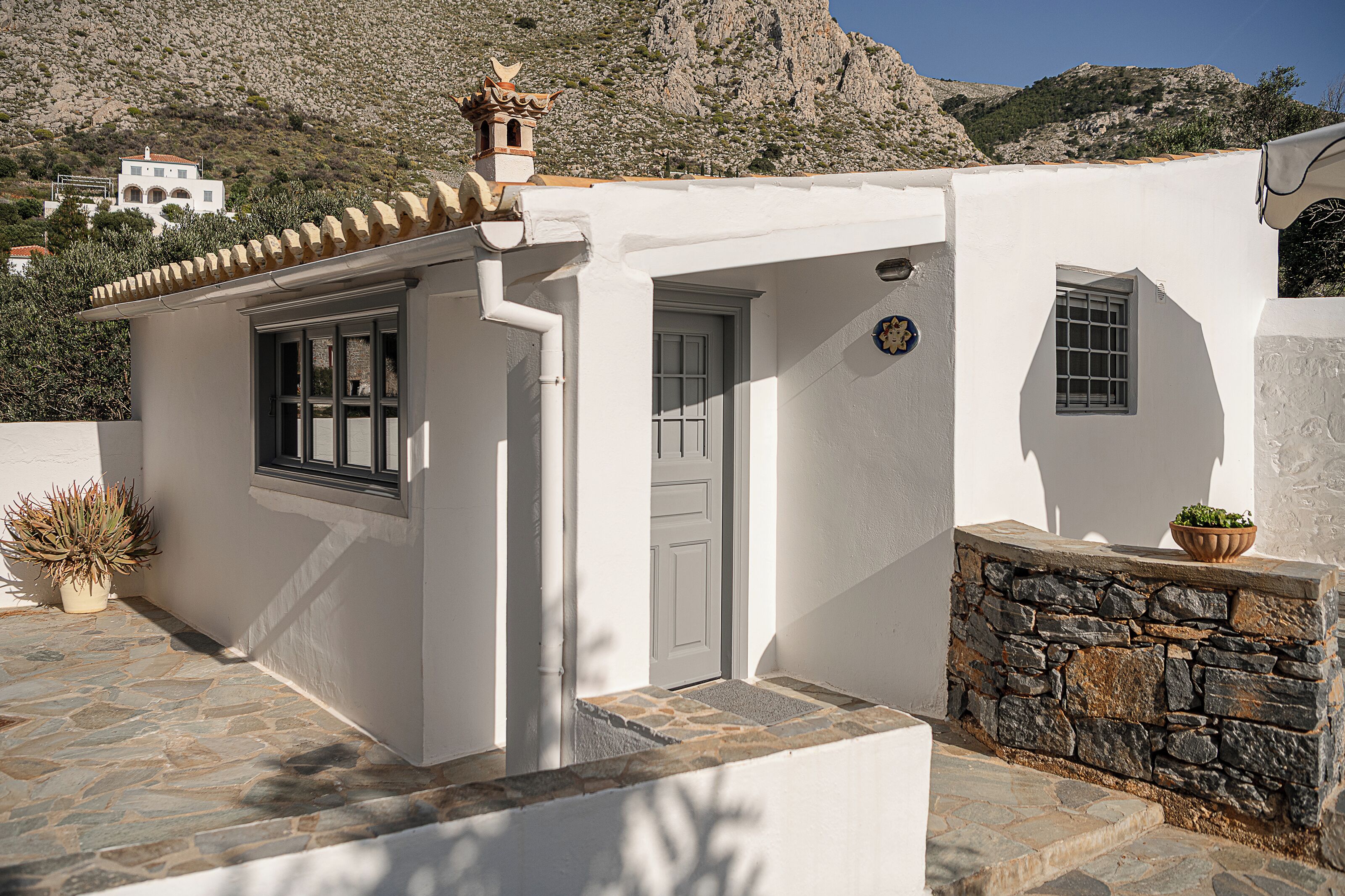 Un edificio blanco con pared de piedra, una puerta y una ventana.