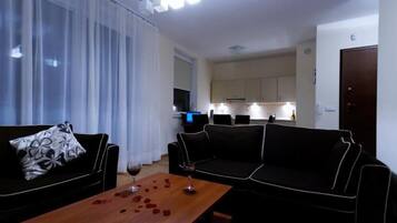 Ein Wohnzimmer mit einer Sofagarnitur, einem Couchtisch mit Rosenblättern und einem Weinglas.