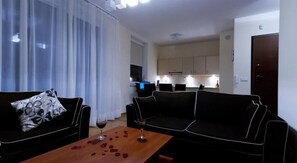 A living room with a sofa set, a coffee table with rose petals, and a wine glass. - Aquamarina (Miedzyzdroje)