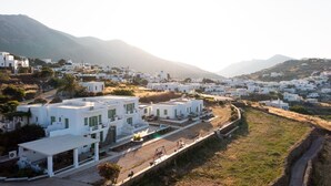 A coastal village with white buildings, a narrow road, and a mountain in the background. - Rooms & Apartments Archontou (Sifnos)