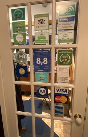 A door with multiple signs indicating high ratings and awards from TripAdvisor, including a 2014 winner and a 2016 Traveler's Choice award. - Repos & Manna Downtown Montreal (Montreal)