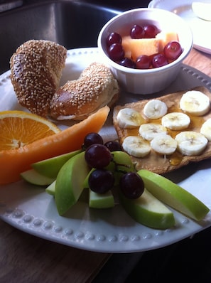 Ein Teller mit einem Sandwich, Obst und einer Schüssel Weintrauben.