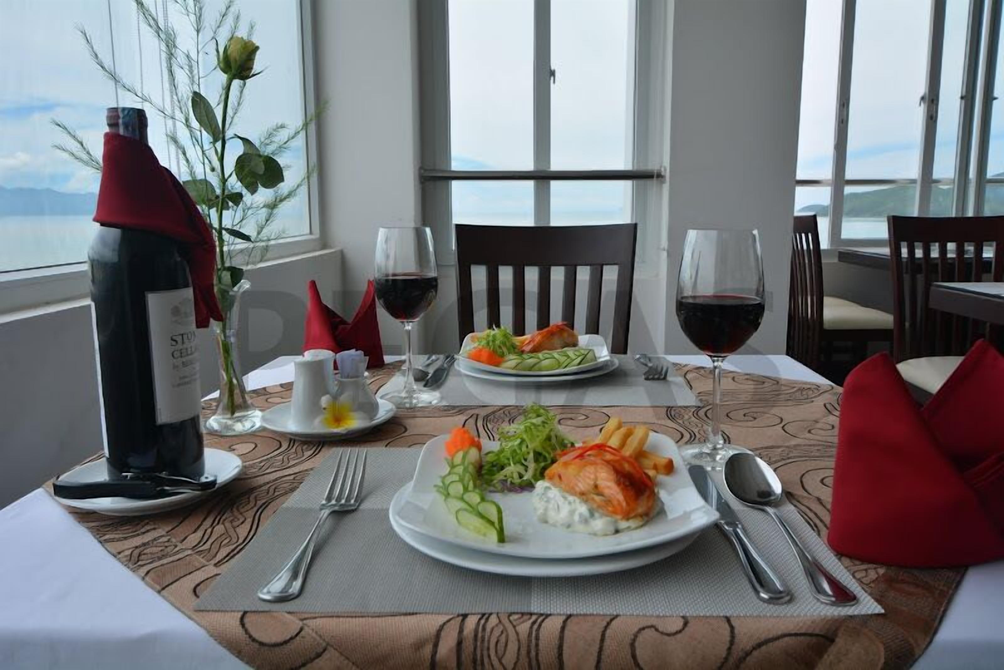 Une table à manger dressée avec des assiettes remplies de nourriture, des verres à vin et des couverts.