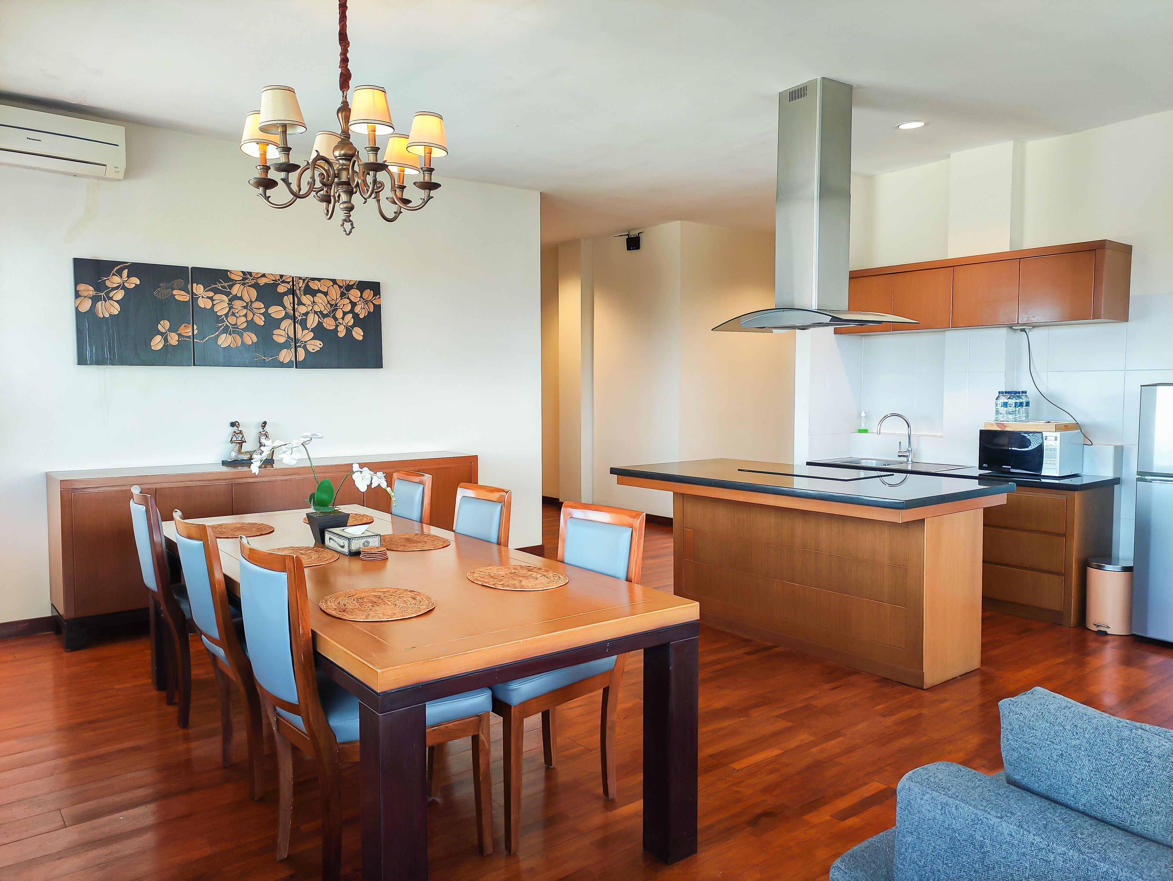 Une cuisine moderne avec un îlot central, une table à manger en bois avec des chaises et un lustre.