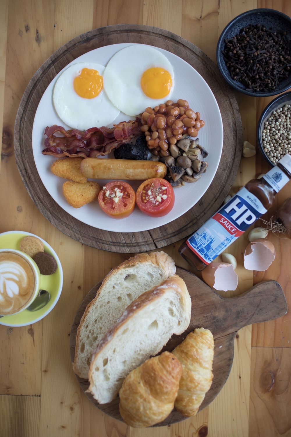 A breakfast plate with eggs, bacon, beans, mushrooms, and tomatoes.