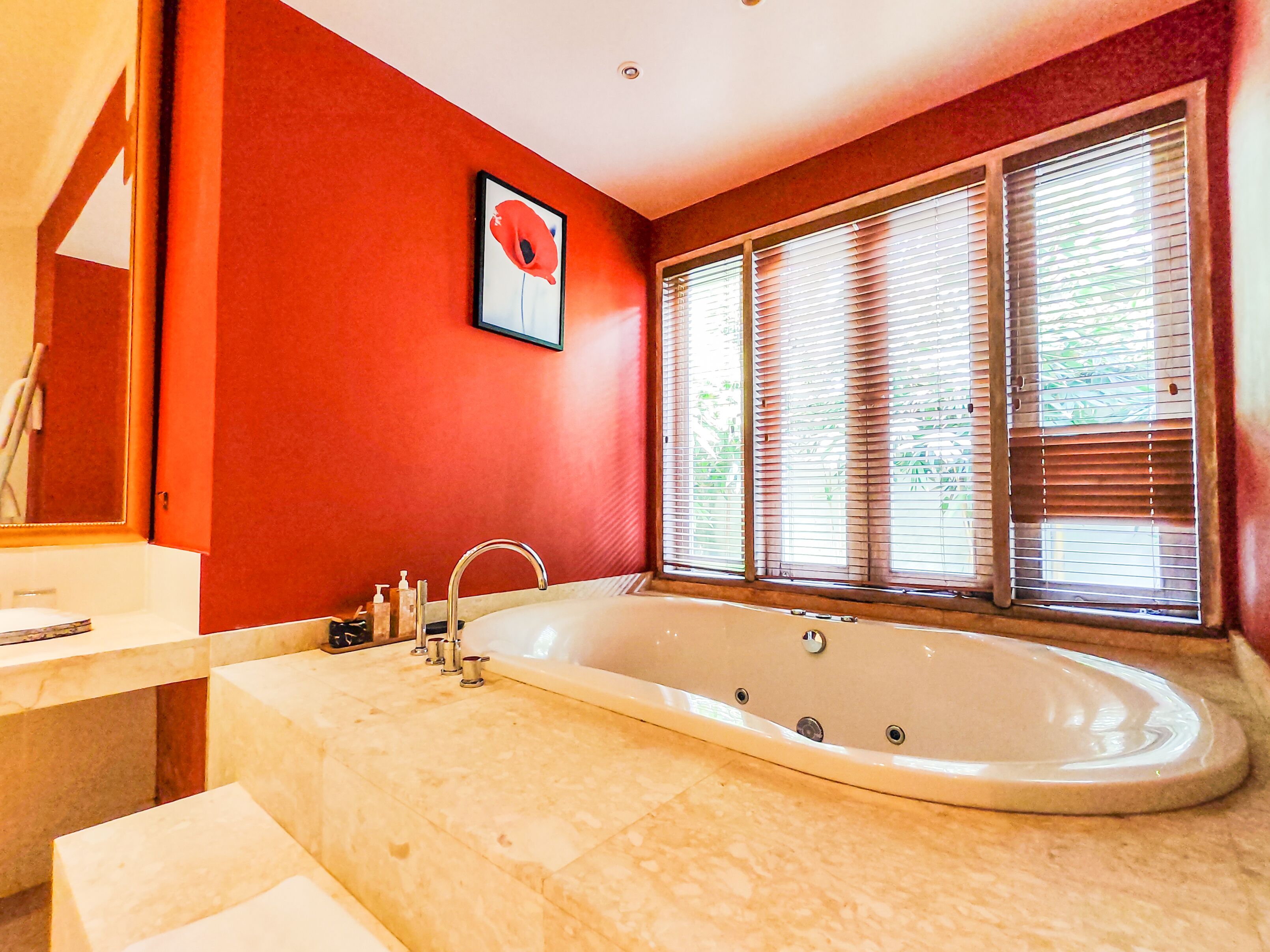 Une salle de bain moderne avec une grande baignoire, un lavabo et une fenêtre équipée de stores.