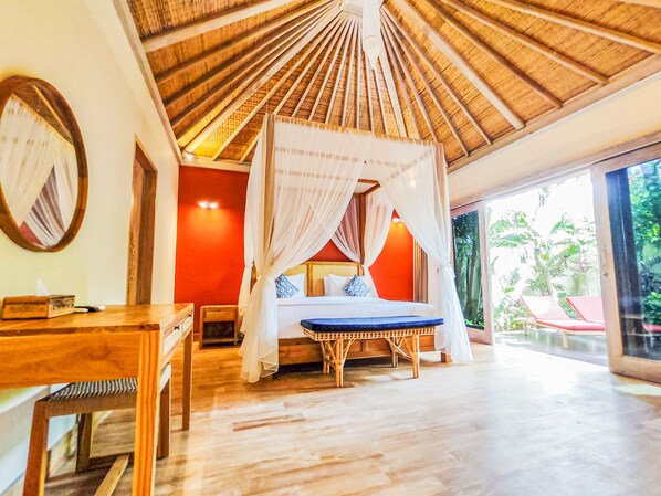 A bedroom with a canopy bed, a wooden table, and a view of the outdoors.