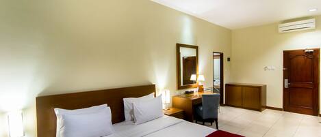 A hotel room with a large bed, a desk, a chair, and a wardrobe.