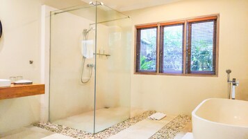 Un bagno moderno con cabina doccia in vetro, una vasca da bagno indipendente e una finestra con persiane.
