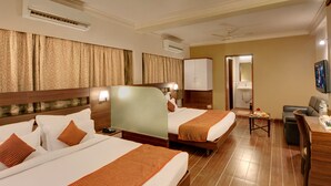 Ein Hotelzimmer mit zwei Betten, einem Schreibtisch, einem Sessel, einem Fernseher und einem durch eine offene Tür einsehbaren Badezimmer.