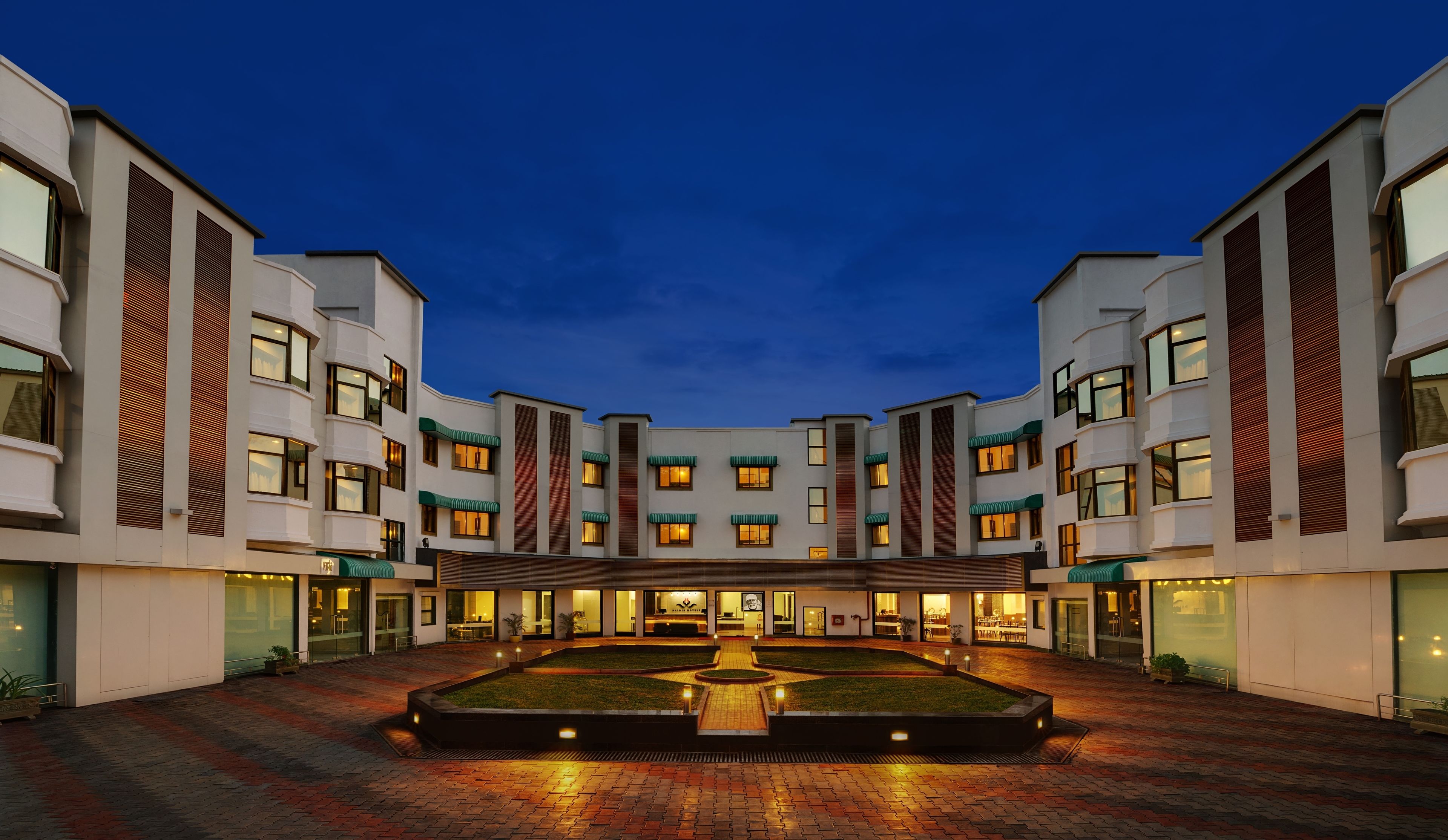 A modern hotel with a central courtyard, multiple floors, and a well-lit entrance.