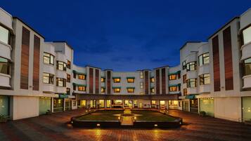 A modern hotel with a central courtyard, multiple floors, and a well-lit entrance.