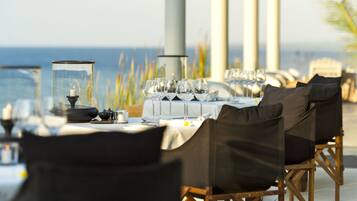 Ein Esstisch mit Meerblick, Sitzgelegenheit im Freien und Kerzen in der Mitte.