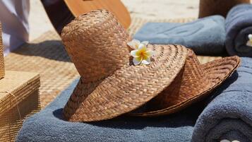 A woven straw hat with a flower, placed on a blue towel.