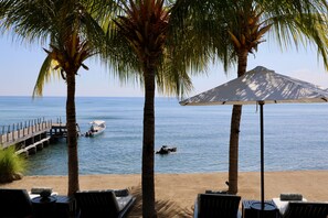 Een privéstrand, wit zand, ligstoelen aan het strand, parasols