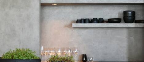A kitchen with a countertop, a black bowl with plants, and wine glasses.