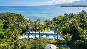 A resort with a pool area surrounded by palm trees and a view of the ocean. - The Lombok Lodge Suites & Private Villas (Tanjung)
