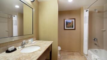 A bathroom with a sink, mirror, shower, and toilet.