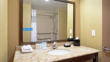 A bathroom with a sink, mirror, and shower.